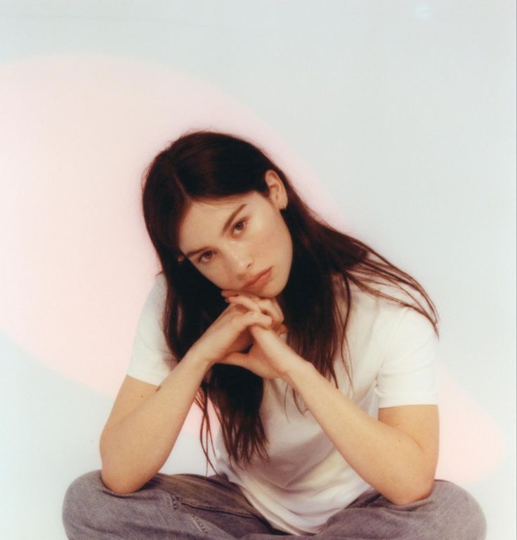 a woman sitting on the ground with her hands under her chin