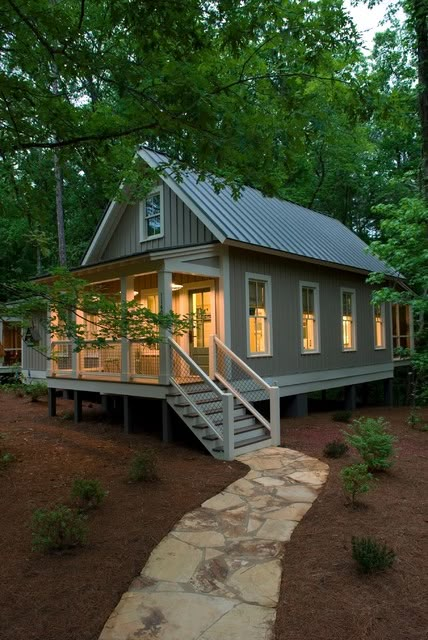 a small house in the woods with stairs leading up to it