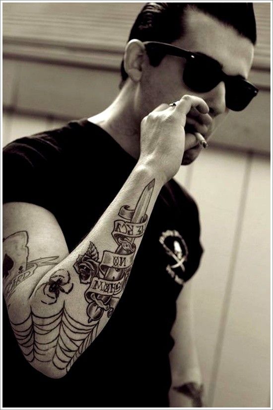 a man with tattoos on his arm and arms holding something in one hand while wearing sunglasses