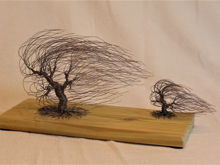 two metal trees sitting on top of a wooden board