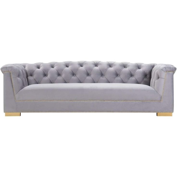 a grey couch with gold trimmings and buttons on the back, against a white background