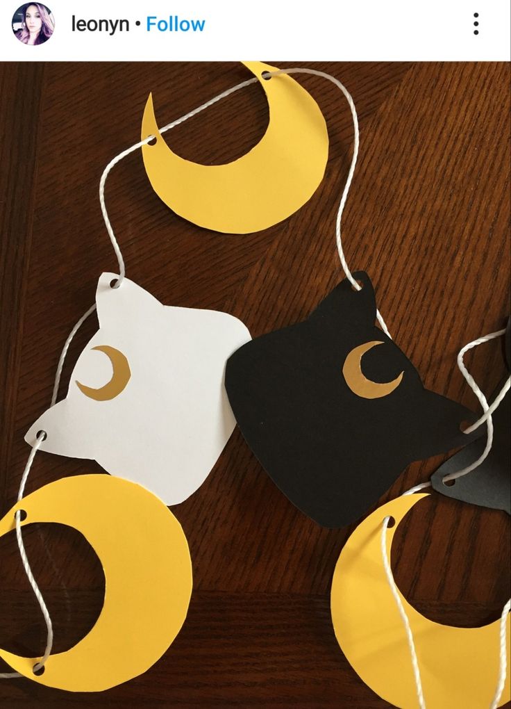 three paper moon and crescent hangings on a wooden table with string attached to them