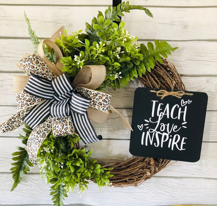 a wreath with a sign that says teach love inspire on it and some greenery