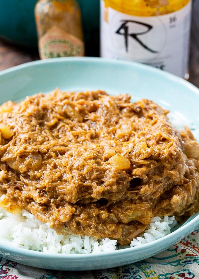 a bowl filled with rice and meat on top of a table next to two bottles