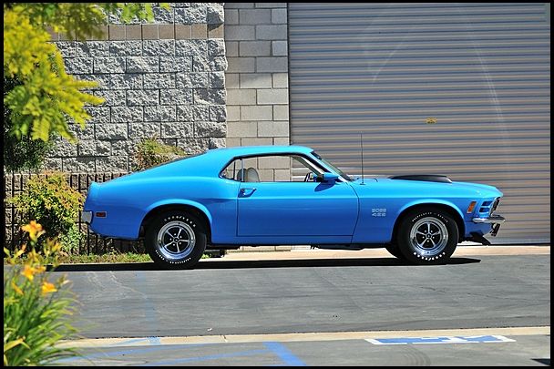 a blue muscle car parked in front of a garage