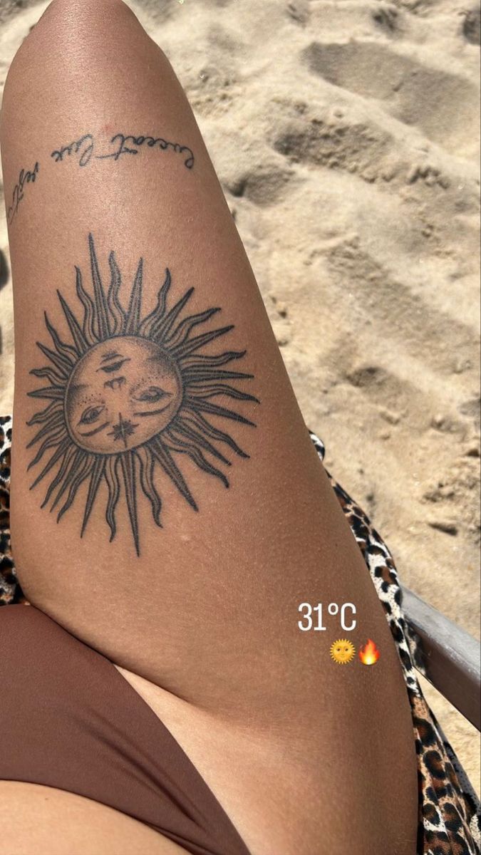 a woman's leg with a sun and moon tattoo on her left side, next to the beach