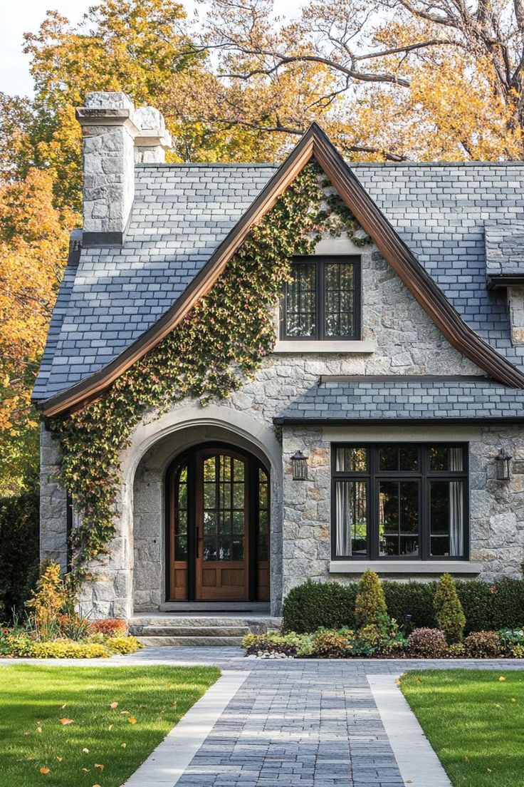 a stone house with ivy growing on the roof and front door, surrounded by lush green grass