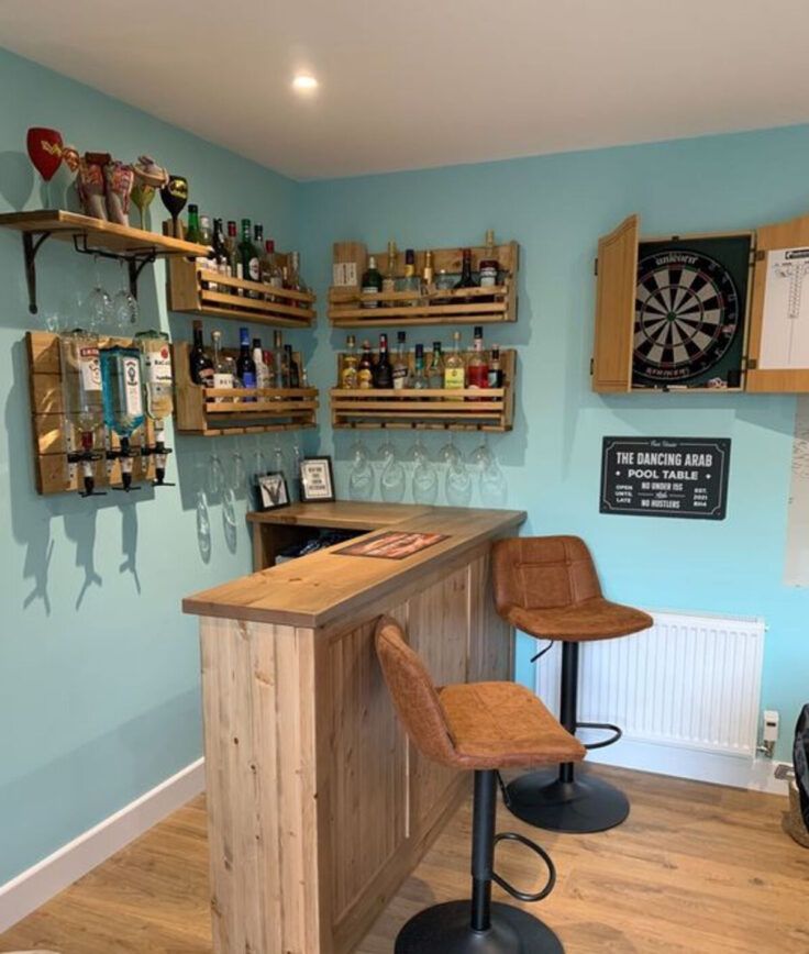 a bar with two stools in front of it and several shelves on the wall