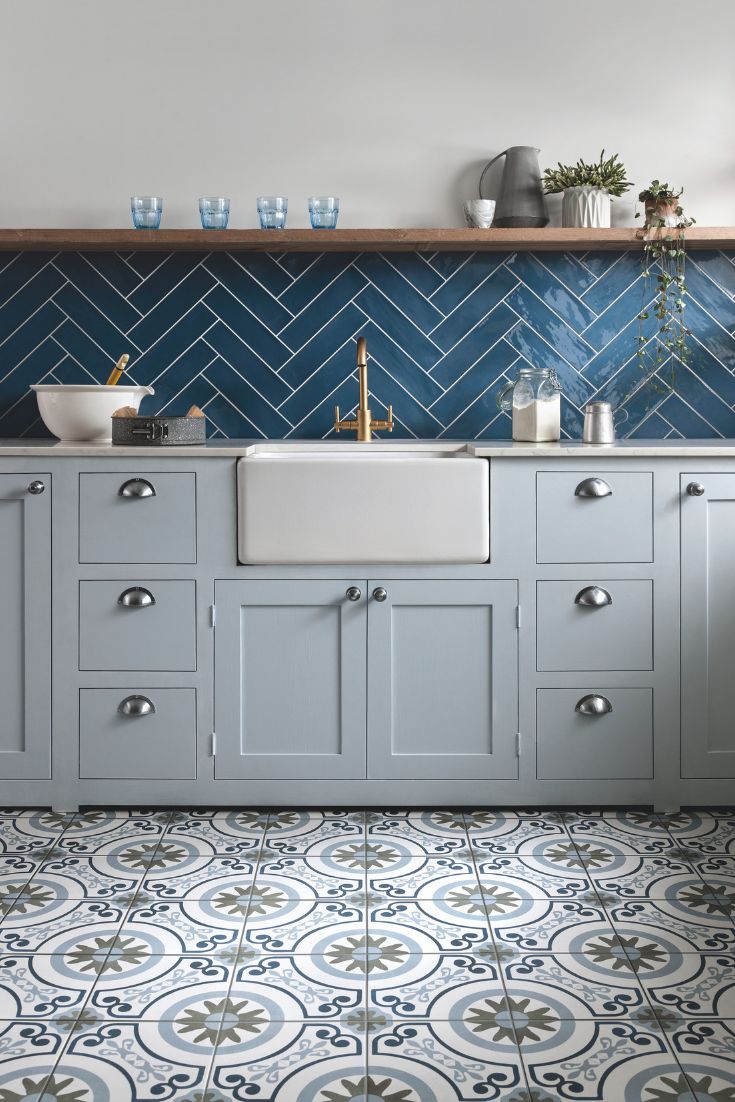 a kitchen with blue and white tiles on the floor, sink and countertop area