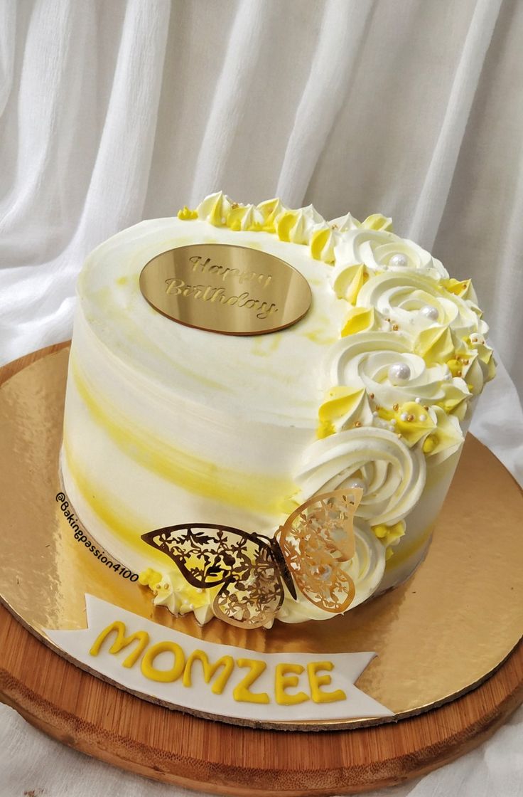 a cake with white frosting and yellow icing on a wooden platter that says monze