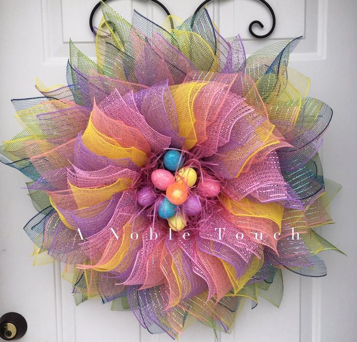 a colorful mesh wreath with candy on it's front door, hanging from a white door