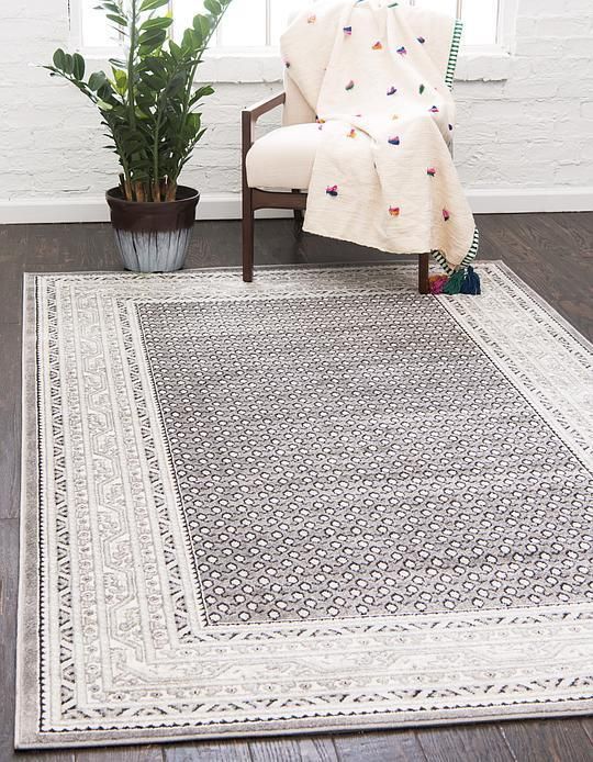 a large rug with an ornate design on the floor in front of a chair and potted plant