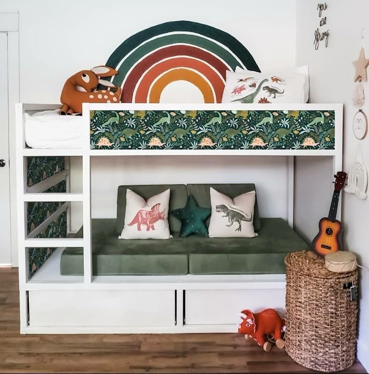 a white bunk bed sitting next to a green couch under a rainbow shaped wall hanging