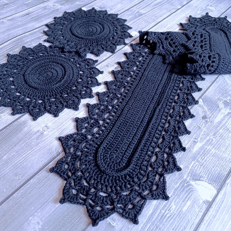 black crocheted doily with tassels on white wooden floor next to scissors