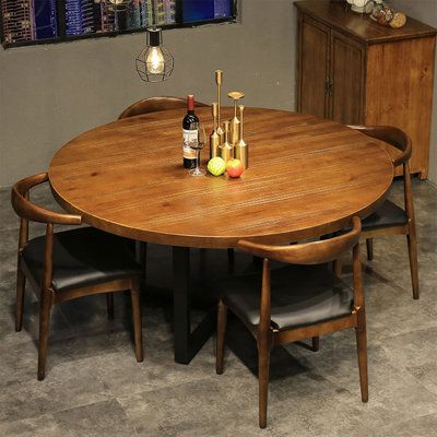 a round wooden table with four chairs around it and bottles of wine on the table