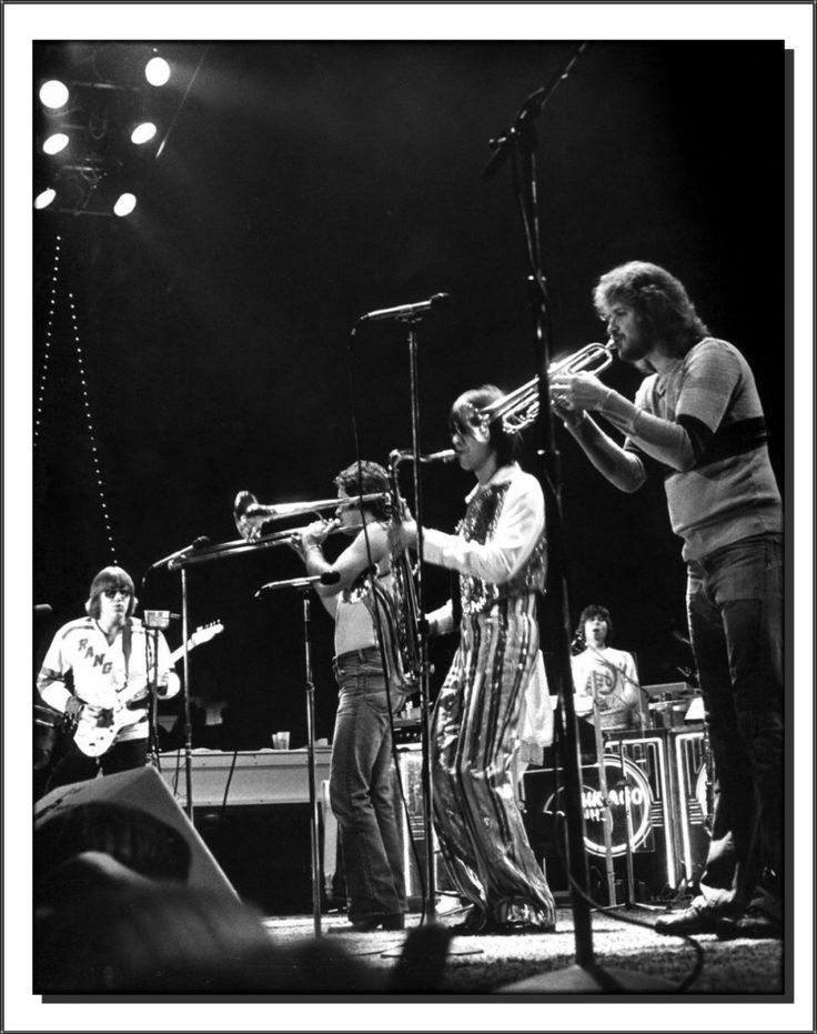 three men are playing instruments on stage