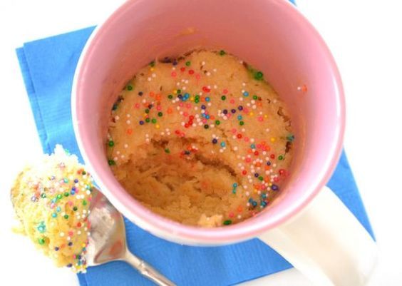 a pink bowl filled with ice cream and sprinkles next to a spoon