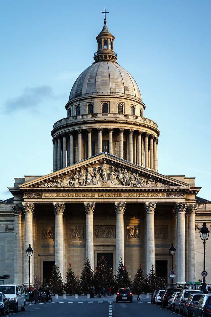 a large building with columns and a dome on the top is surrounded by cars parked in front