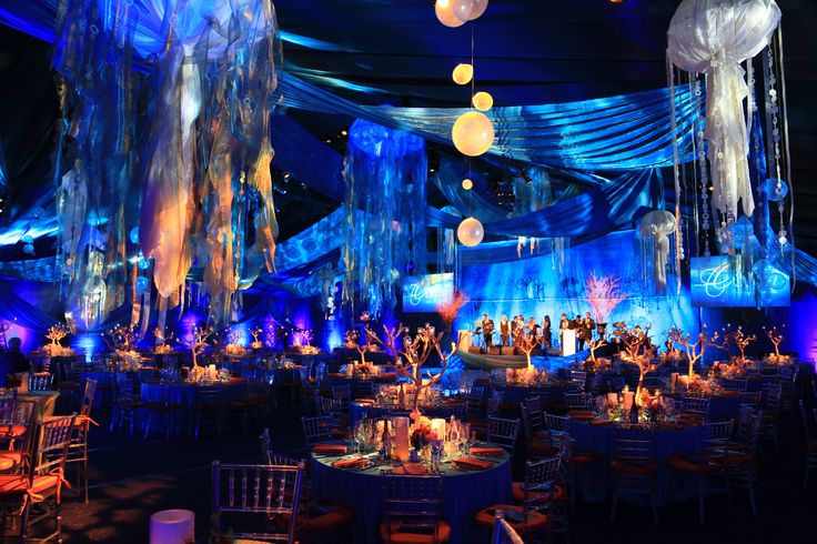 a large room filled with lots of tables covered in white and blue clothed decorations