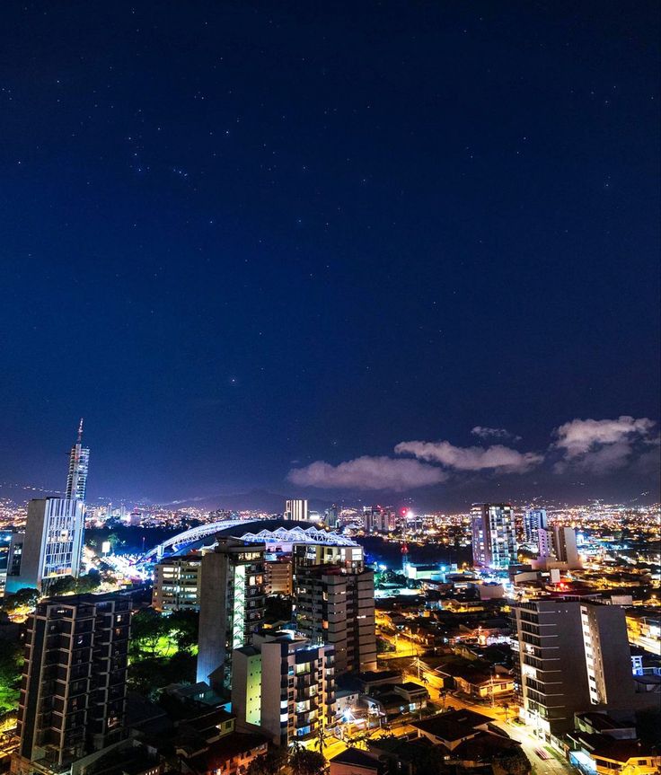 the night sky is lit up with stars and clouds in the cityscape, as well as skyscrapers