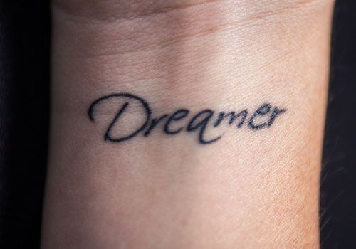 a small wrist tattoo with the word dream on it