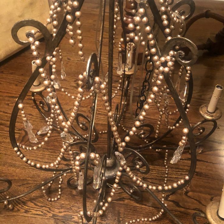 a metal chandelier with pearls and chains hanging from it's sides on a wooden floor