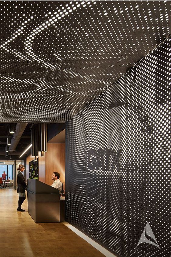 people are standing in an office lobby with black and white patterns on the wall behind them