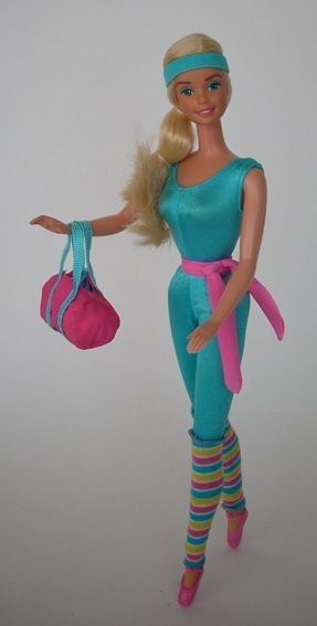 a barbie doll with blonde hair and blue outfit holding a pink purse in her hand