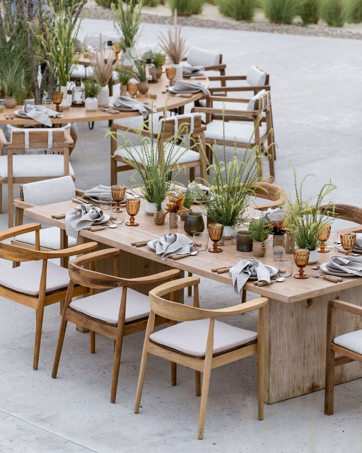 an outdoor dining area with wooden tables and chairs, potted plants on each table