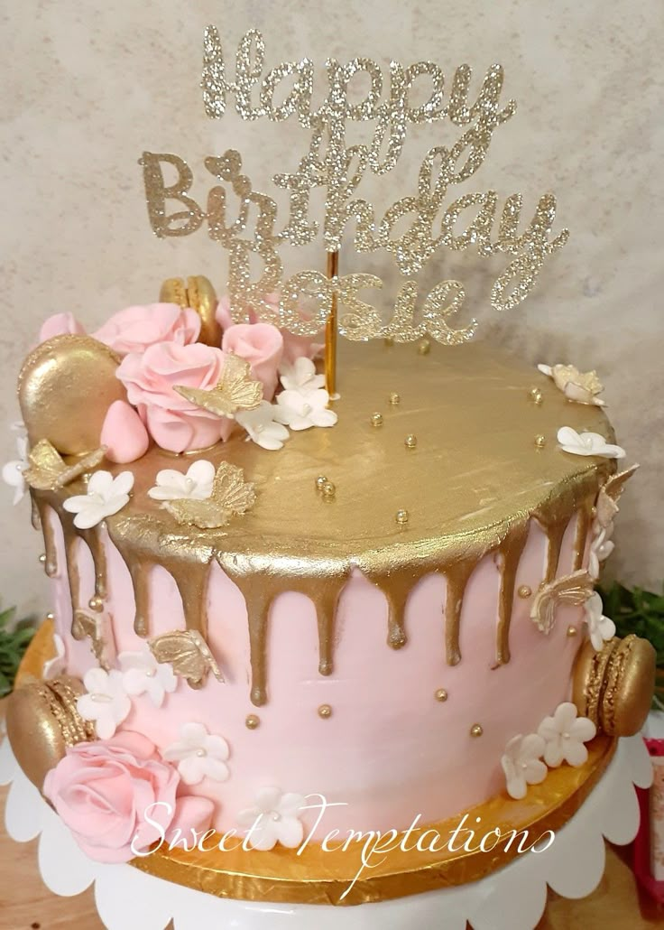 a pink and gold birthday cake decorated with flowers