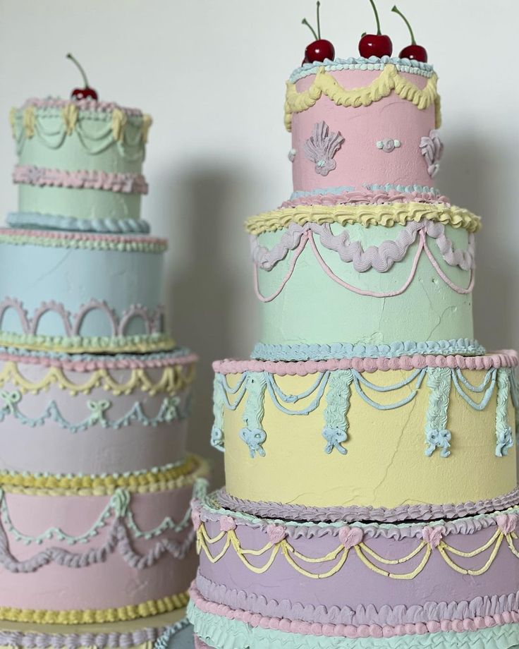 three tiered cakes with cherries on top and ribbons around the edges, all decorated in pastel colors