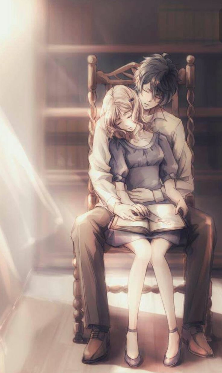 two people sitting on a chair in front of a bookshelf with their arms around each other