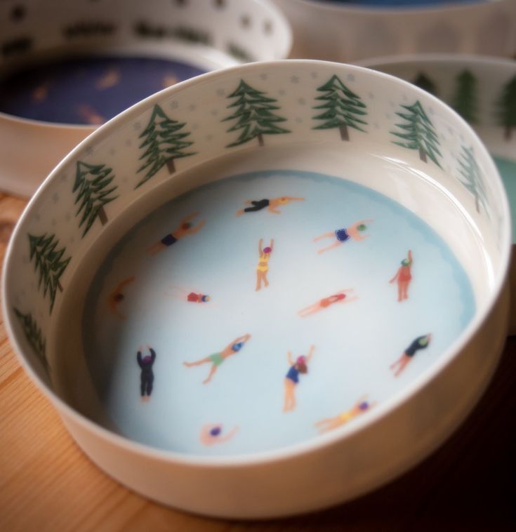 two bowls with people in the water and trees painted on them are sitting on a table