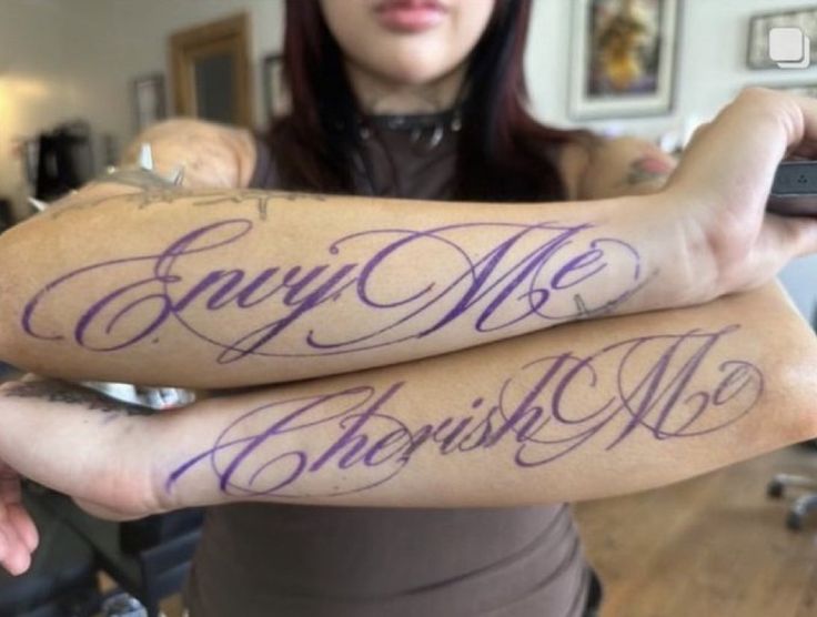 two people with tattoos on their arms holding remotes