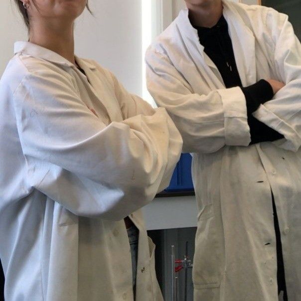 two people in lab coats standing next to each other