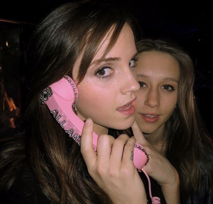 two young women are talking on the telephone