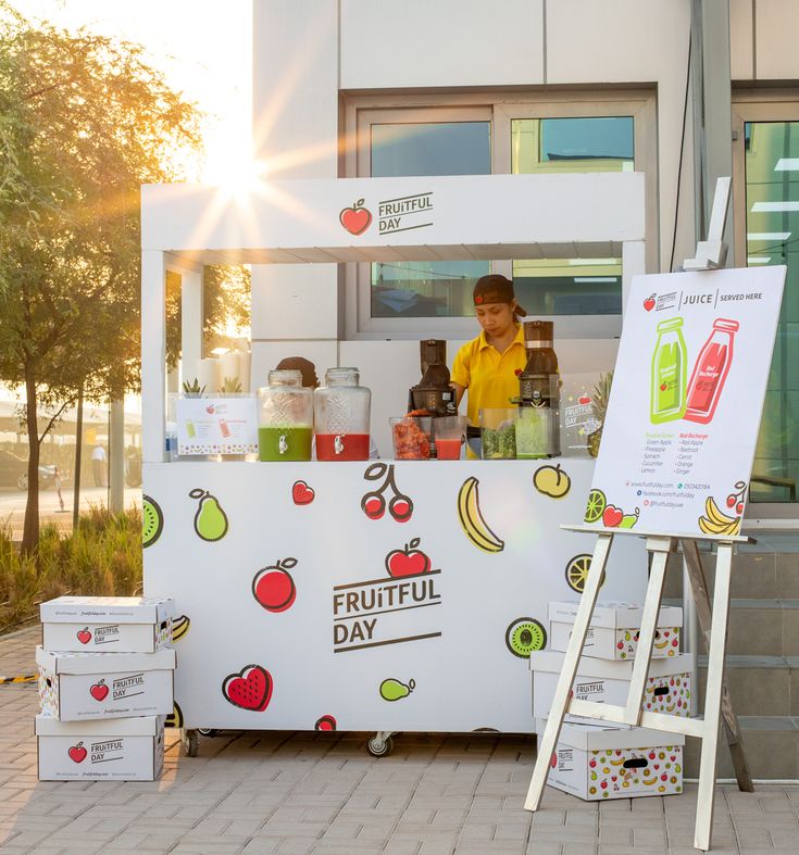 a man standing behind a fruit juice stand