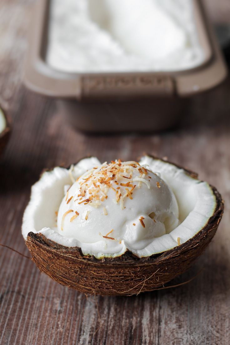 a coconut shell filled with ice cream on top of a wooden table next to an empty container