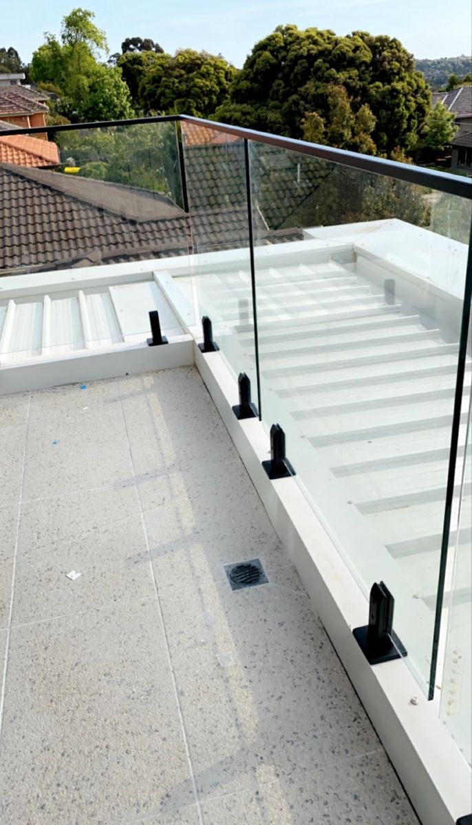 a white bench sitting on top of a cement floor next to a metal rail and glass railing