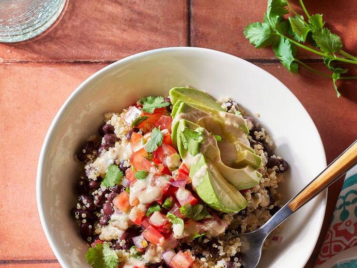 a bowl filled with rice, beans and avocado on top of a table