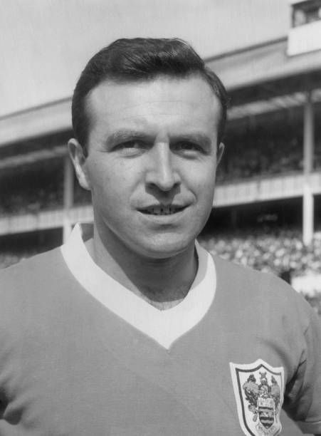 a black and white photo of a man wearing a soccer uniform in front of a stadium