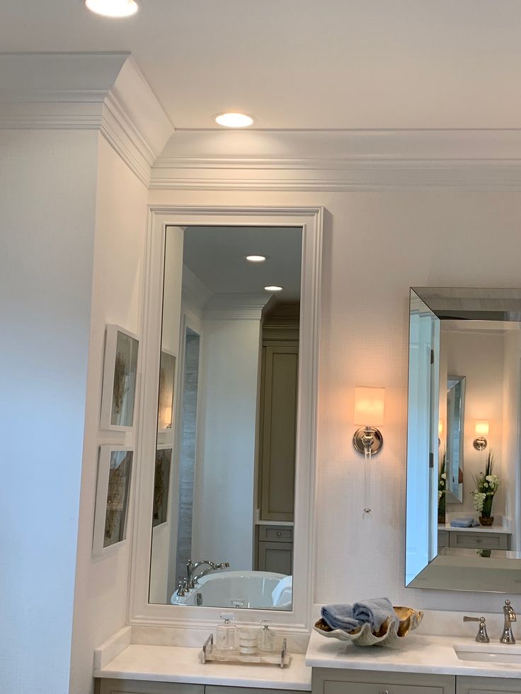 a bathroom with two sinks, mirrors and lights on the wall above them is shown