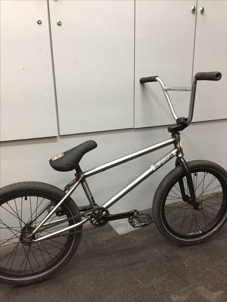 a bike parked in front of a white wall and some metal bars on the handlebars