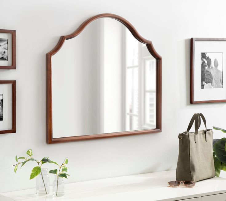 a mirror sitting on top of a white counter next to a purse and potted plant