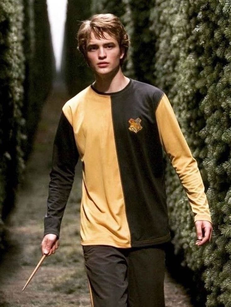 a young man walking down a path with a wand in his hand and trees behind him