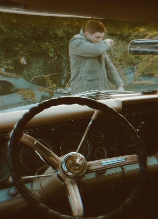 a man standing behind the steering wheel of a car