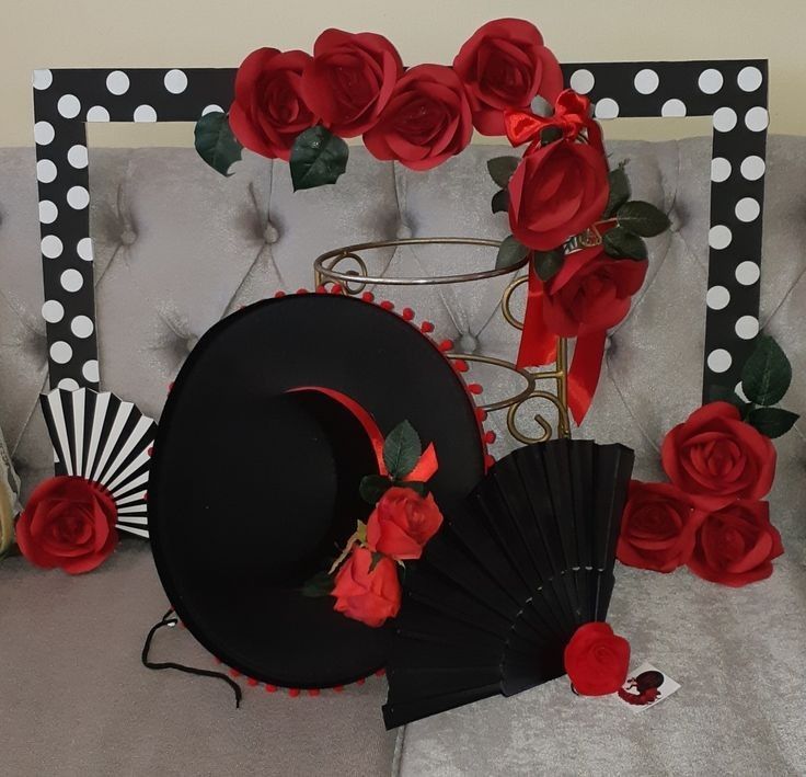 a black hat with red roses on it next to a fan and other items that are sitting on a couch