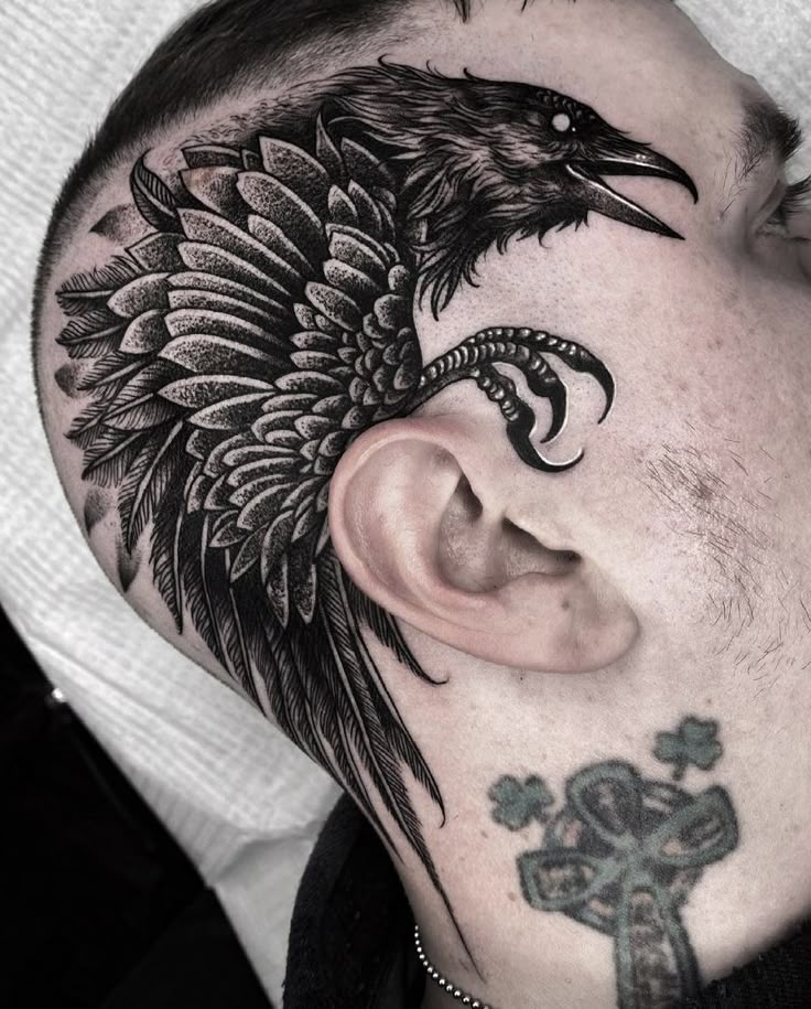 a man with a tattoo on his face and neck has a cross behind him, which is decorated with a crow