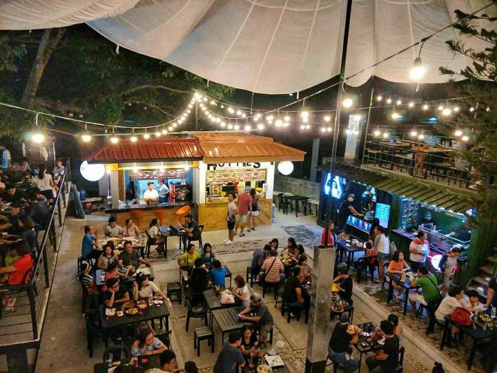 an overhead view of people sitting at tables in a restaurant with lights strung from the ceiling