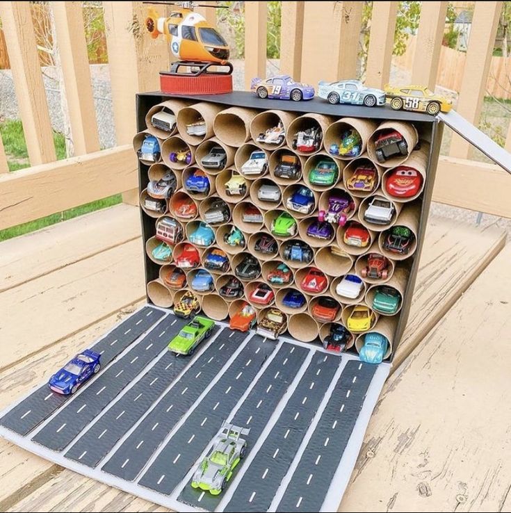 a toy car race track made out of cardboard tubes on a deck with a truck in the background